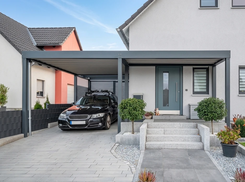 Abri de voiture double (carport) moderne en acier, toit plat gris anthracite, structure tubulaire, fixé au sol sur pavés