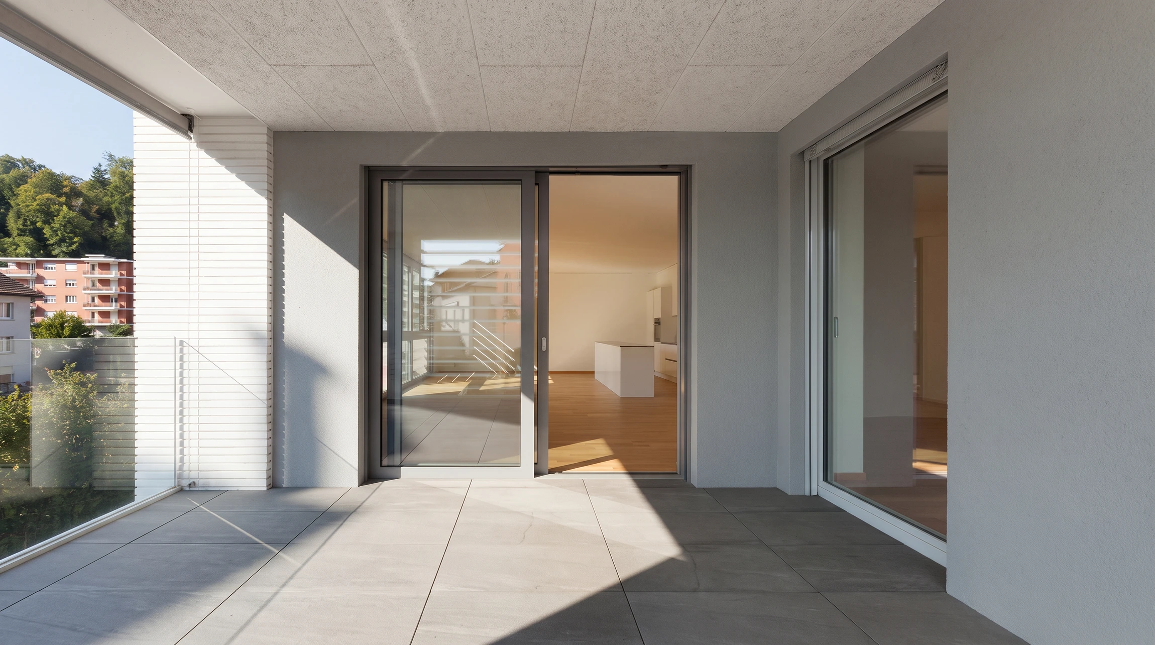 Extension vitrée contemporaine accolée à une maison en pierre, avec toit plat monopente en zinc anthracite et lanterneau